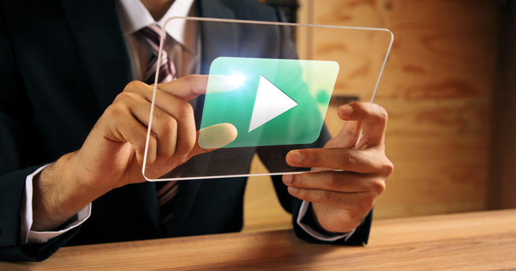 A businessman holding a video on glass